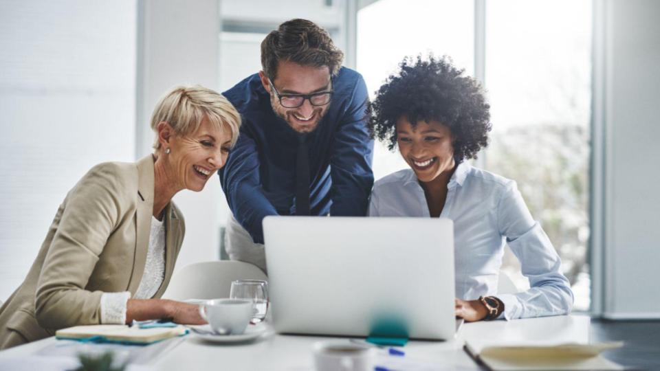 Three revenue team members smile while examinging sales pipeline growth and closed deals.