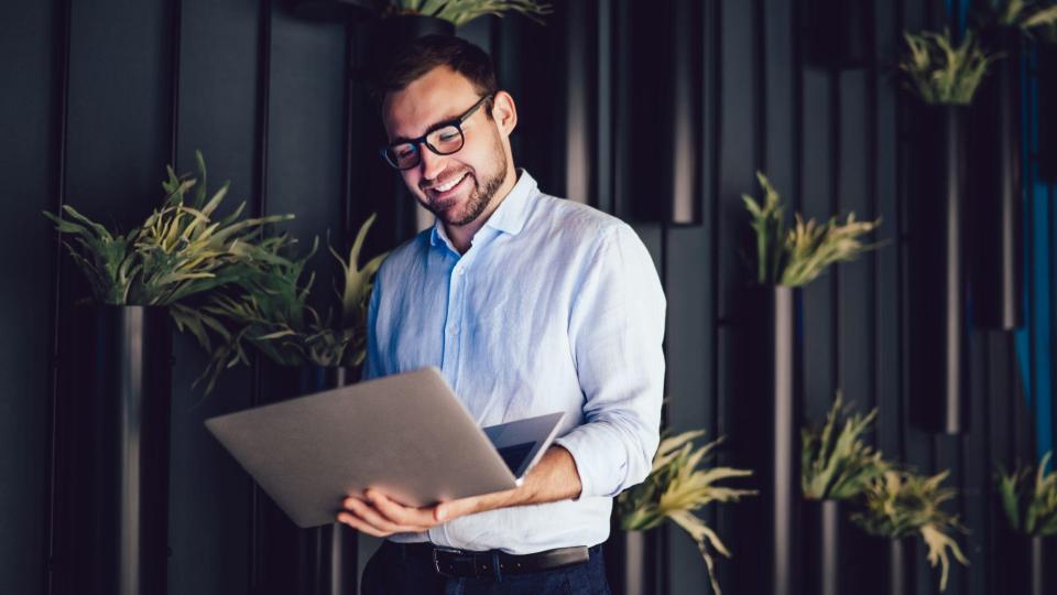 Cheerful marketer in optical spectacles reading email with good news about corporate analytics.