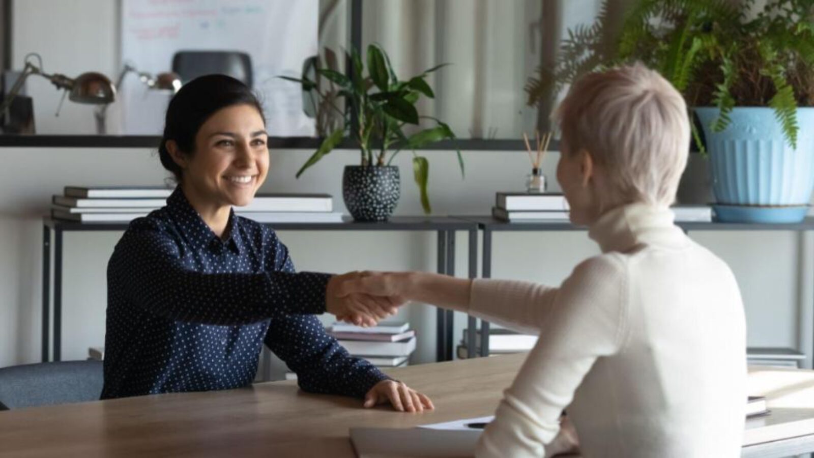 A Sales rep shakes hands with a customer during an in-person meeting