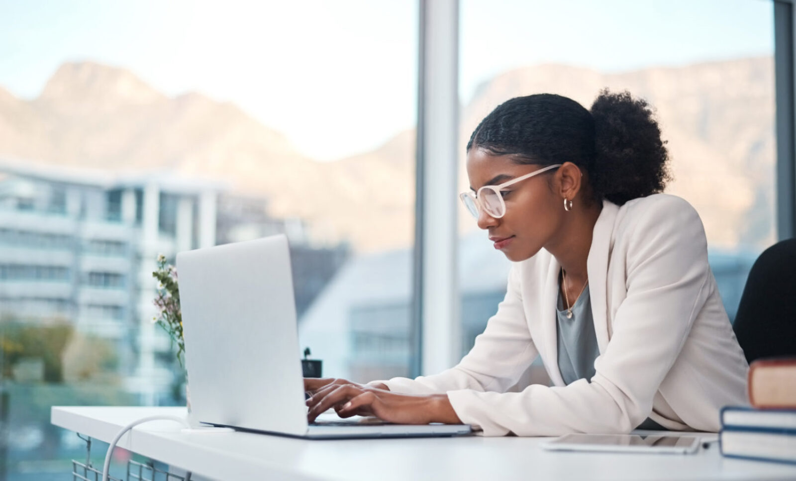 Data professional and secretary typing an email on a laptop and doing online research while working in an office. African entrepreneur looking focused while using the internet for work.