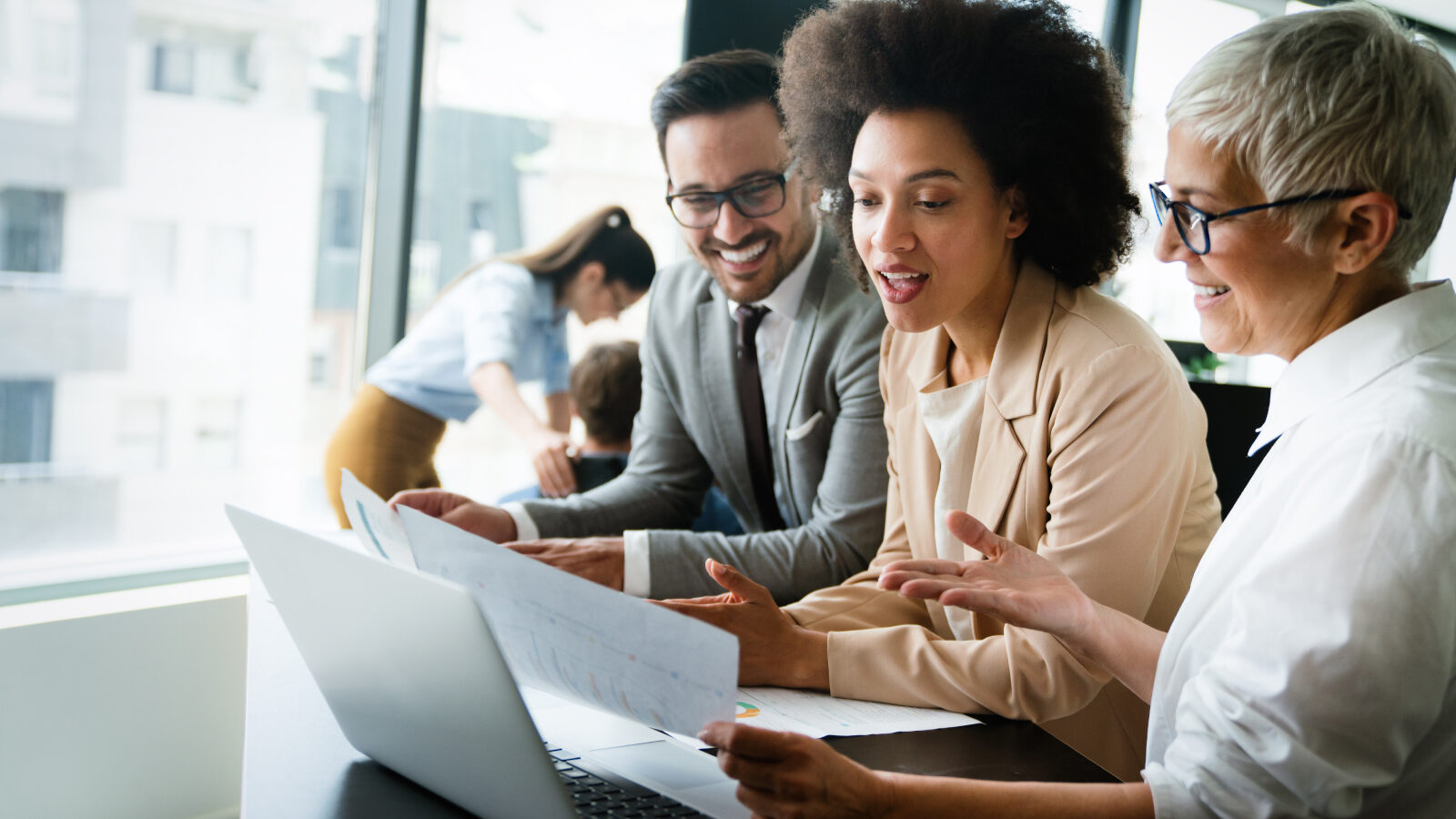 Channel partners sit around a laptop sharing account insights.