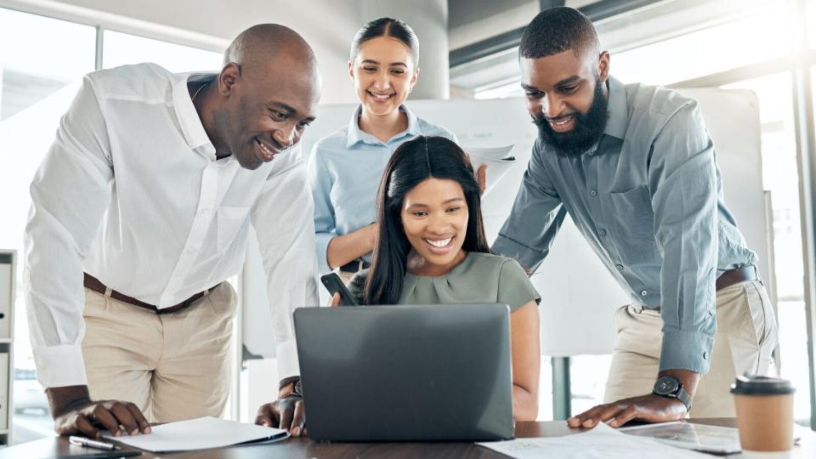 Four revenue team members gather at one of their desks to examine prospect accounts