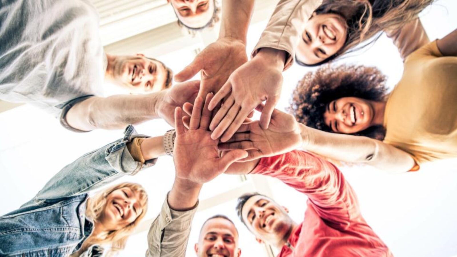 Five people smile during a sales meeting.