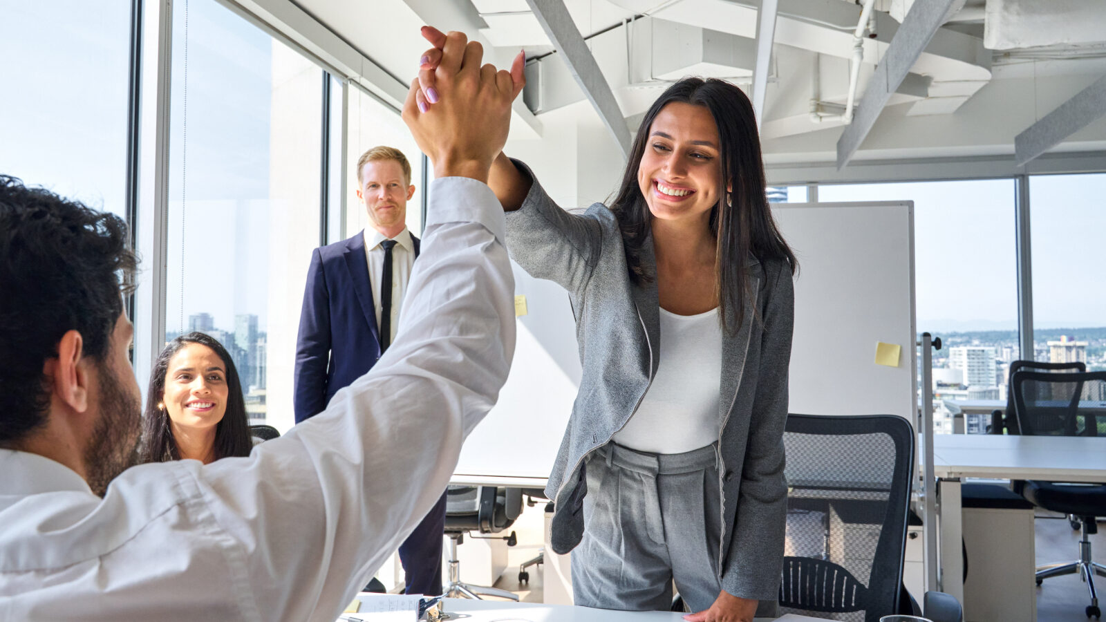 Two sales reps high five after a successful upsell